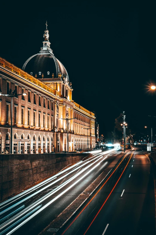 an old historic building at night with the lights from passing cars