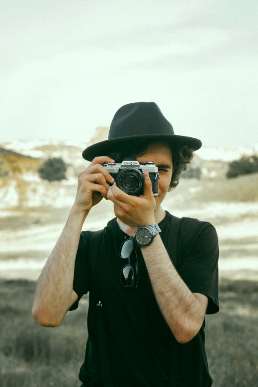 man wearing hat takes pograph with camera