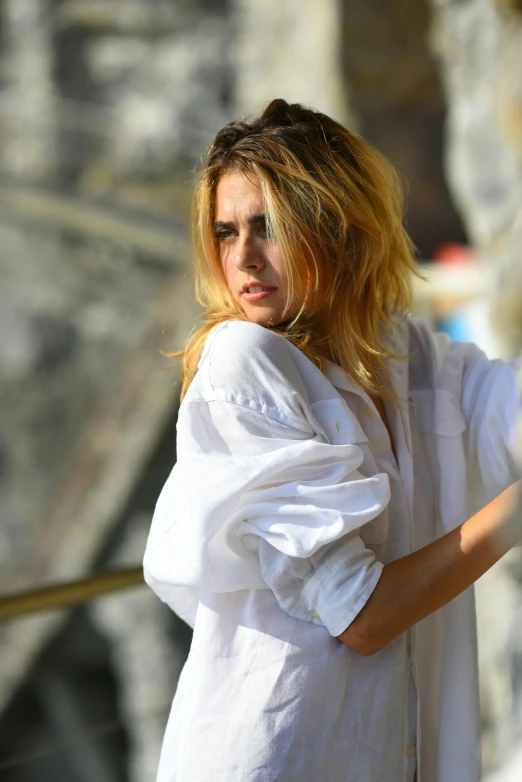 a woman wearing a white shirt poses with her arms crossed