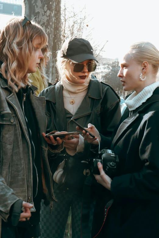 two women, one of them using her phone, are talking to another person