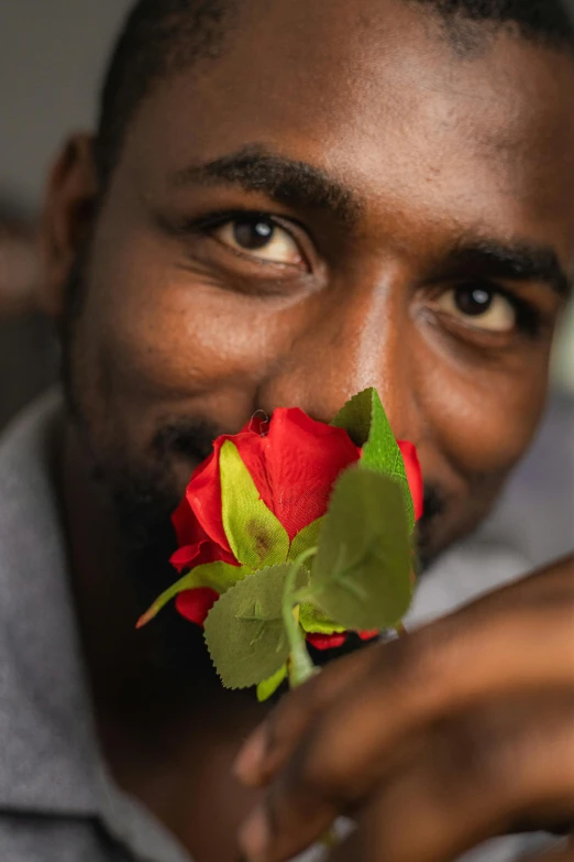 the man has a red rose with green leaves in his mouth