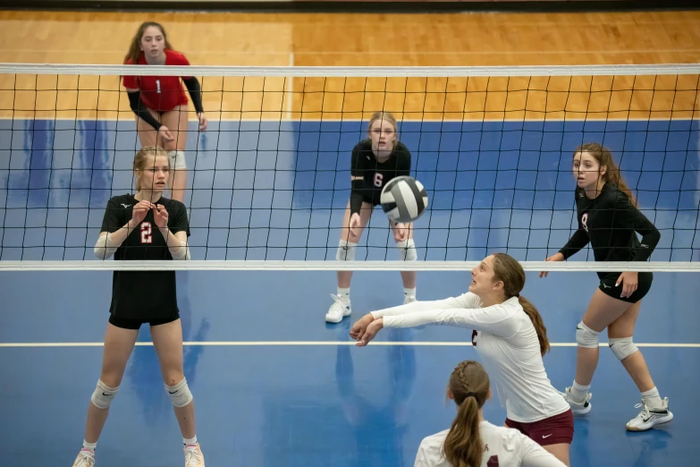 four women playing volley ball in a gymnasium