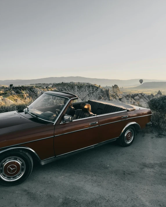 a classic automobile is parked along side some rocks