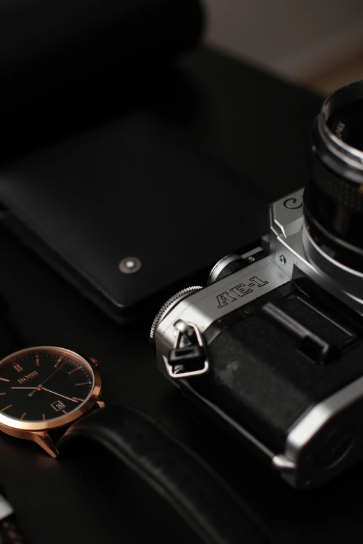 a watch, camera and lens are on a table