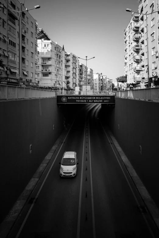 a white car drives down the road in a tunnel