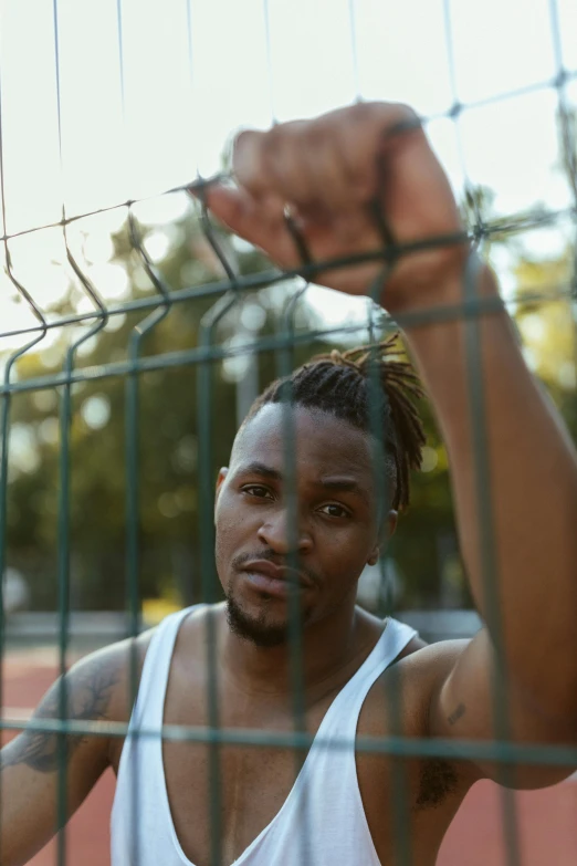 a man holds his fist up and stands in front of a fence