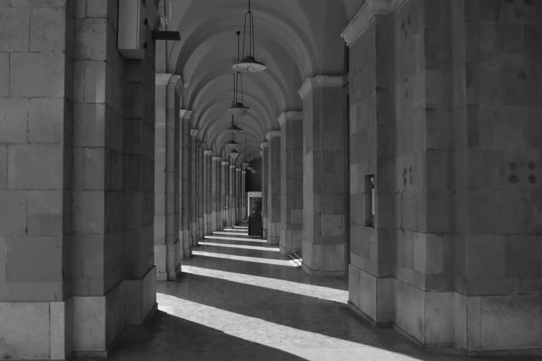 an arched corridor leading into a building with columns