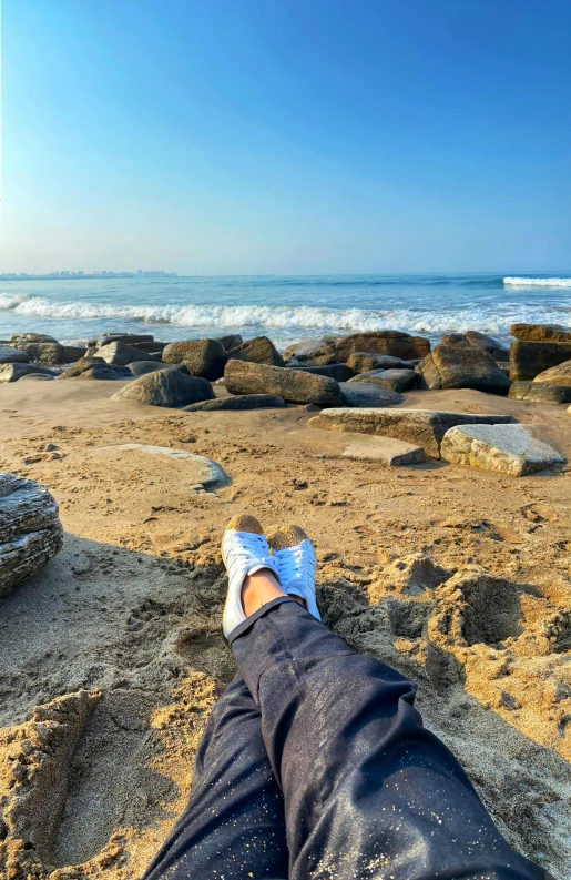 someone has their feet up on the beach sand