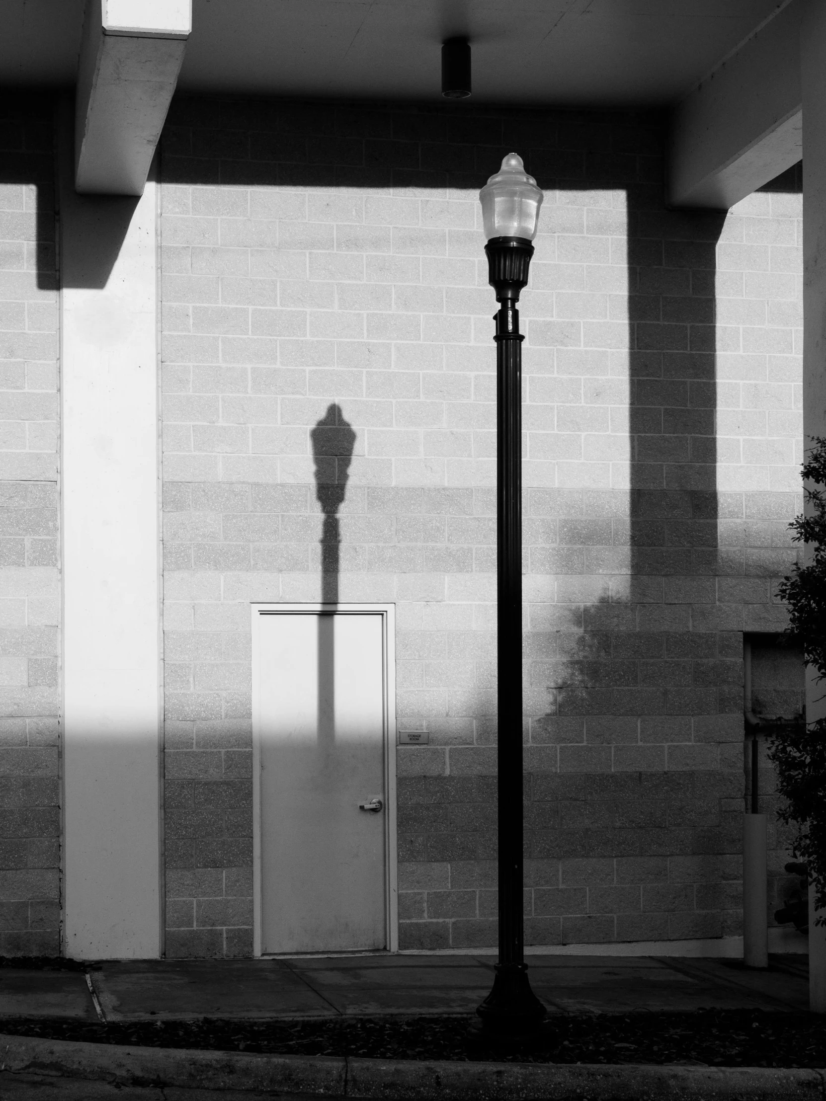 a street lamp next to a tall brick wall