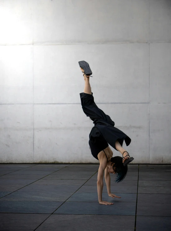 young person balancing on one foot on gray concrete