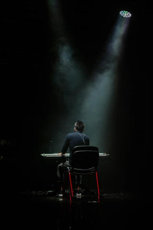 a man sitting in a chair under two spotlights