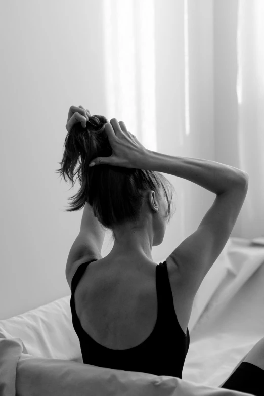 a woman sitting on a bed with a tank top on