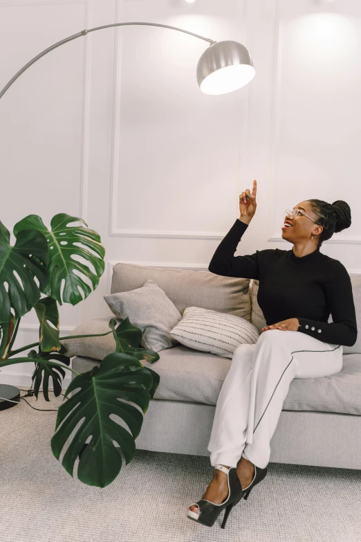 woman wearing black sitting on a couch waving at the sun