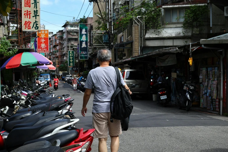 man walking in an alley with scooters and shops