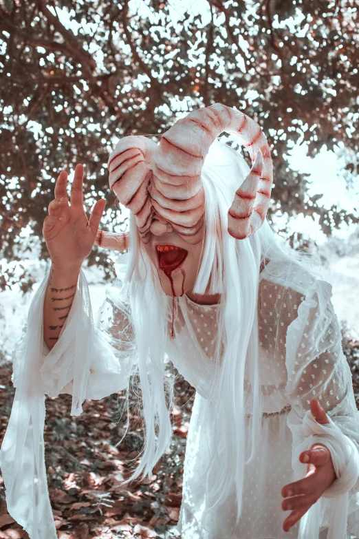 a person wearing a scary white costume, and holding soing up in front of them