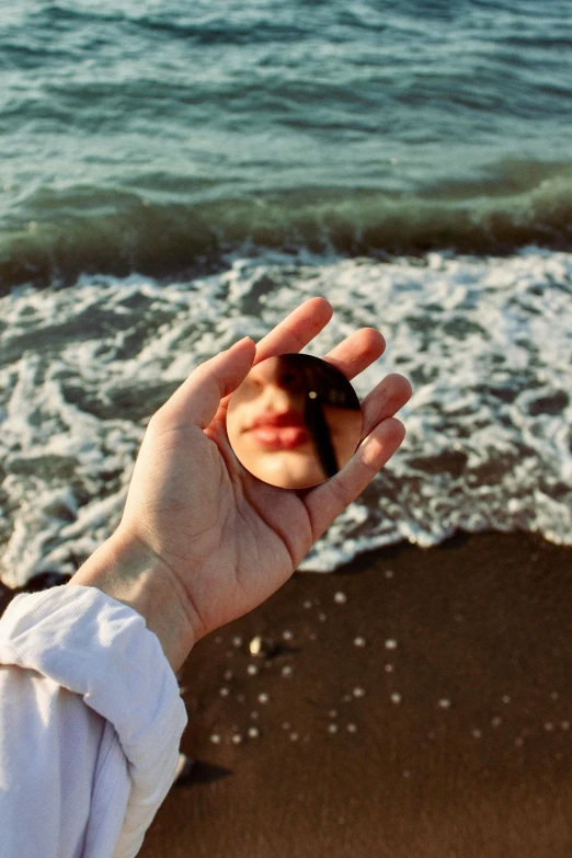 a hand holds up an object over the ocean