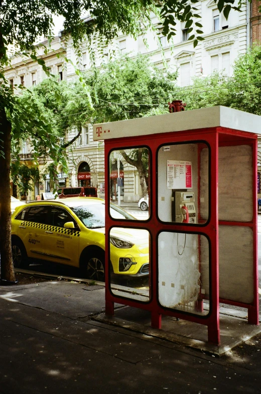 a taxi cab is parked in front of a public phone booth