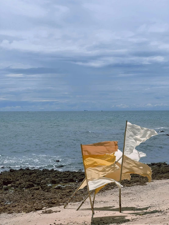 two empty beach chairs sitting on top of a rocky shore