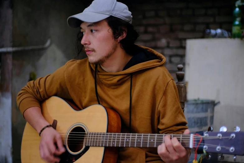 a man wearing a cap plays a guitar