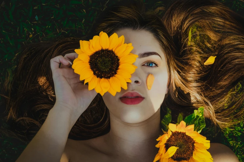 a young woman laying on top of a field with yellow sunflowers