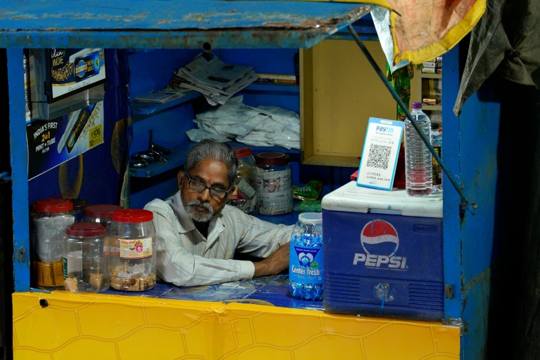 an old man standing in front of a blue and yellow stand