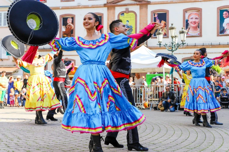 some people are wearing colorful costumes and dance in the street