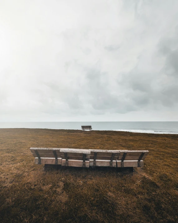 a lone bench sits in a field that looks out into the distance