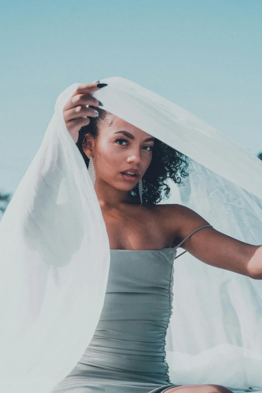 a young woman sitting on the ground under a sheet