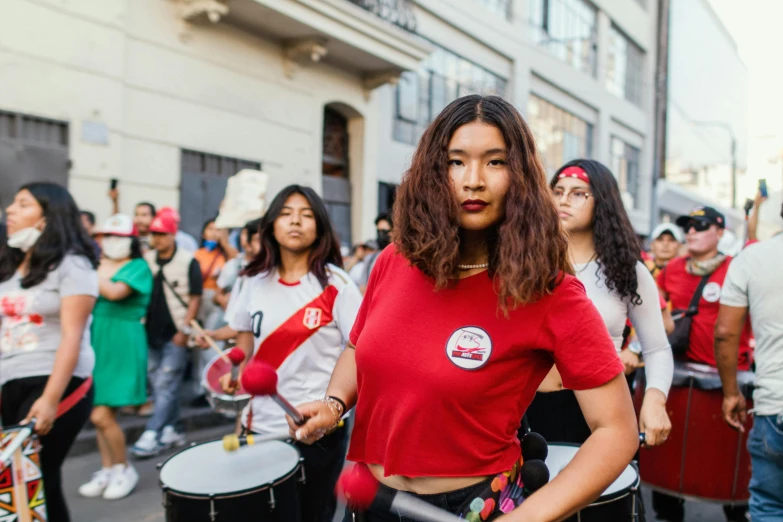 people standing on the street while some are dressed as women playing drums