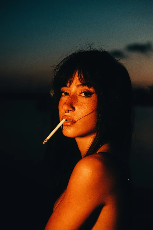 the woman is smoking a cigarette by the water