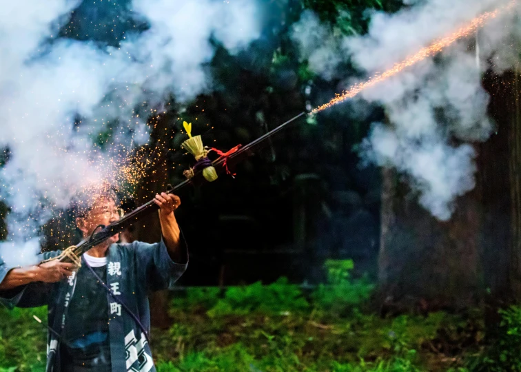 a person standing on some grass holding onto a pipe with smoke coming out