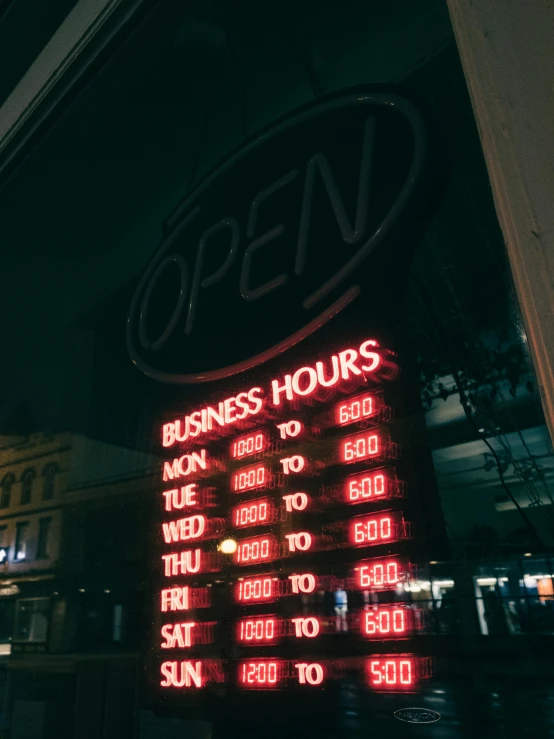 a red light sits on the sign for open hours