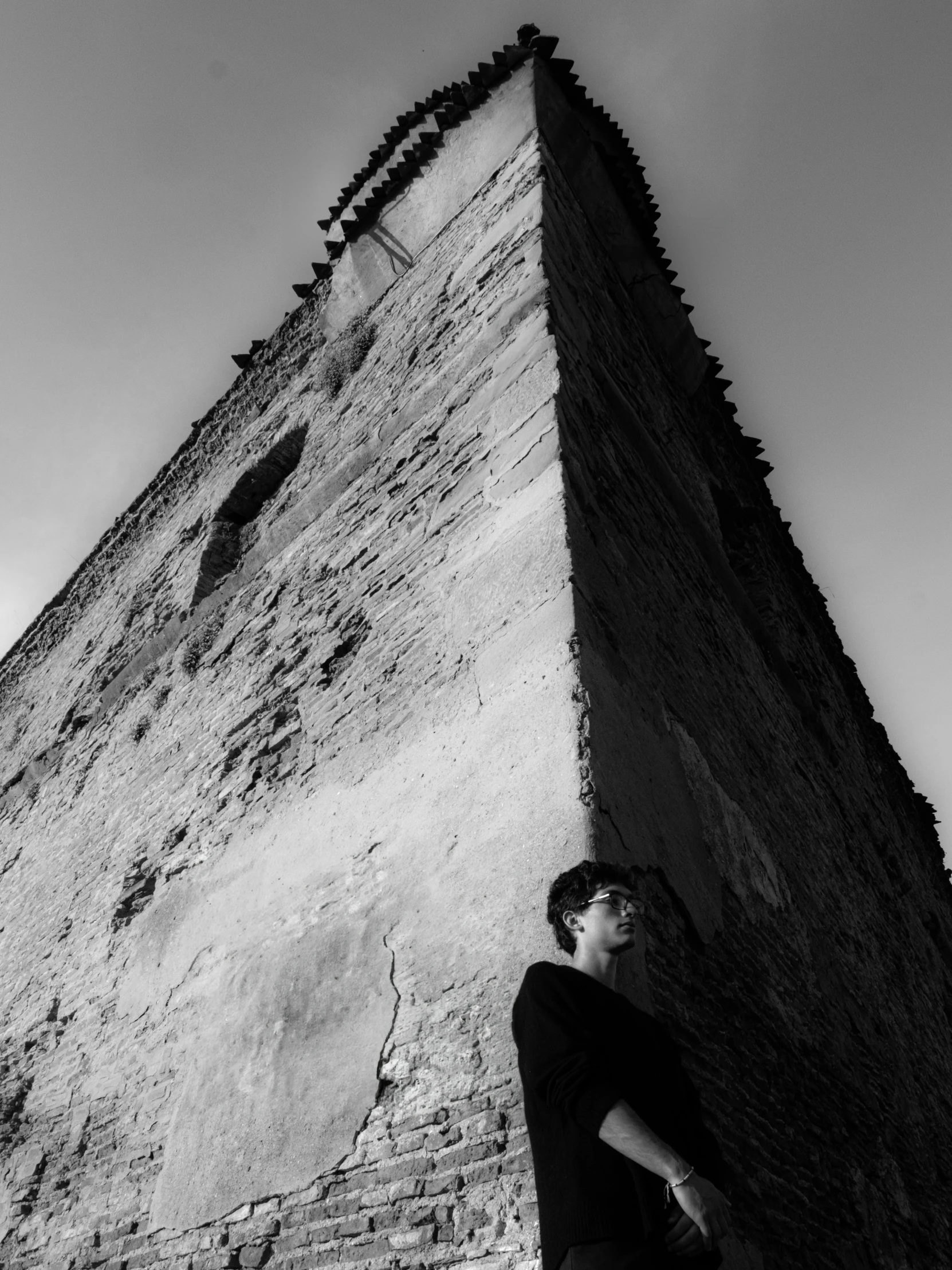 a man leaning against the side of a tall stone building