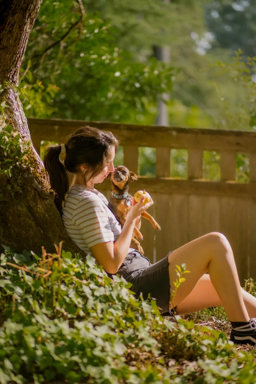 a young woman sitting on a wooden deck with a dog