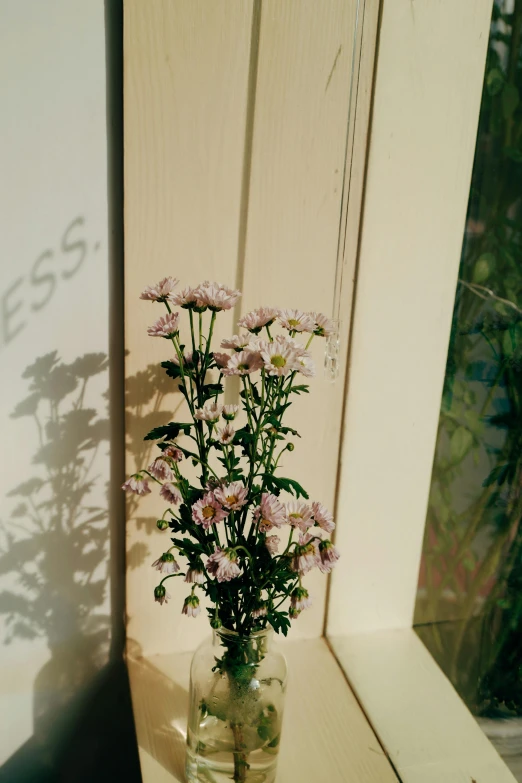 a vase with flowers on the side of a window