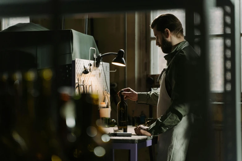 a man pouring wine from a bottle into a glass on top of a table