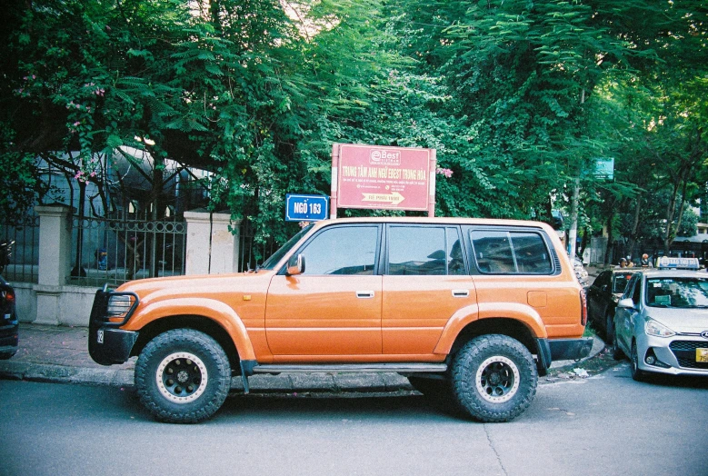 an orange four doored suv parked on the side of a street