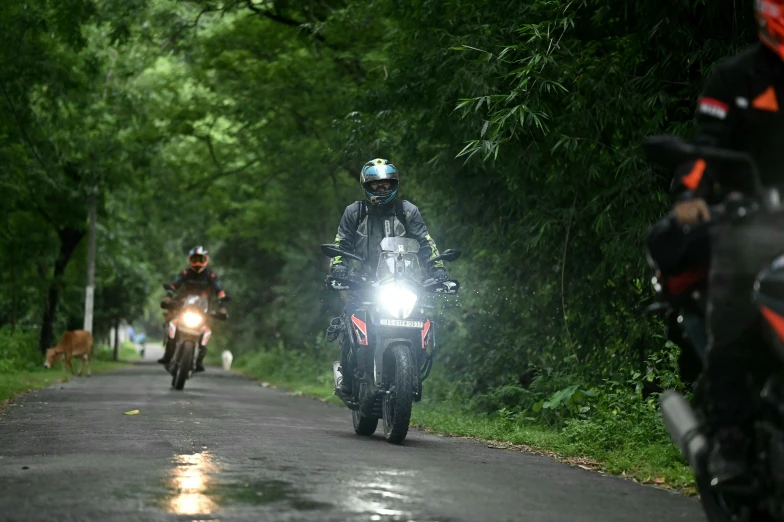 two people riding motorcycles down a road at night