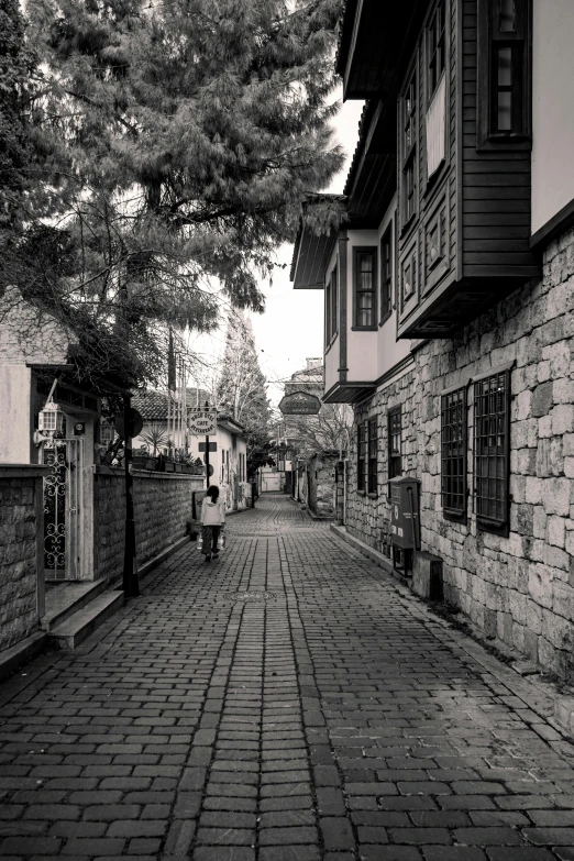 a person walking down an old street past a brick building