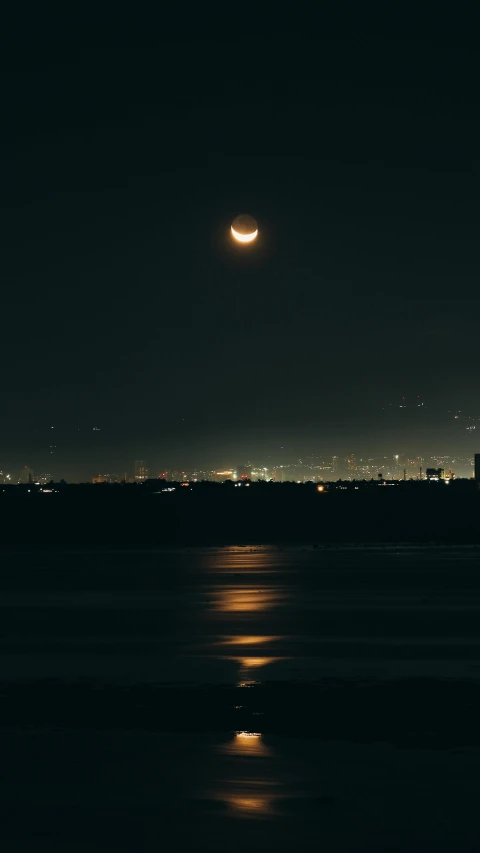 a moon in the sky with a small building in the background