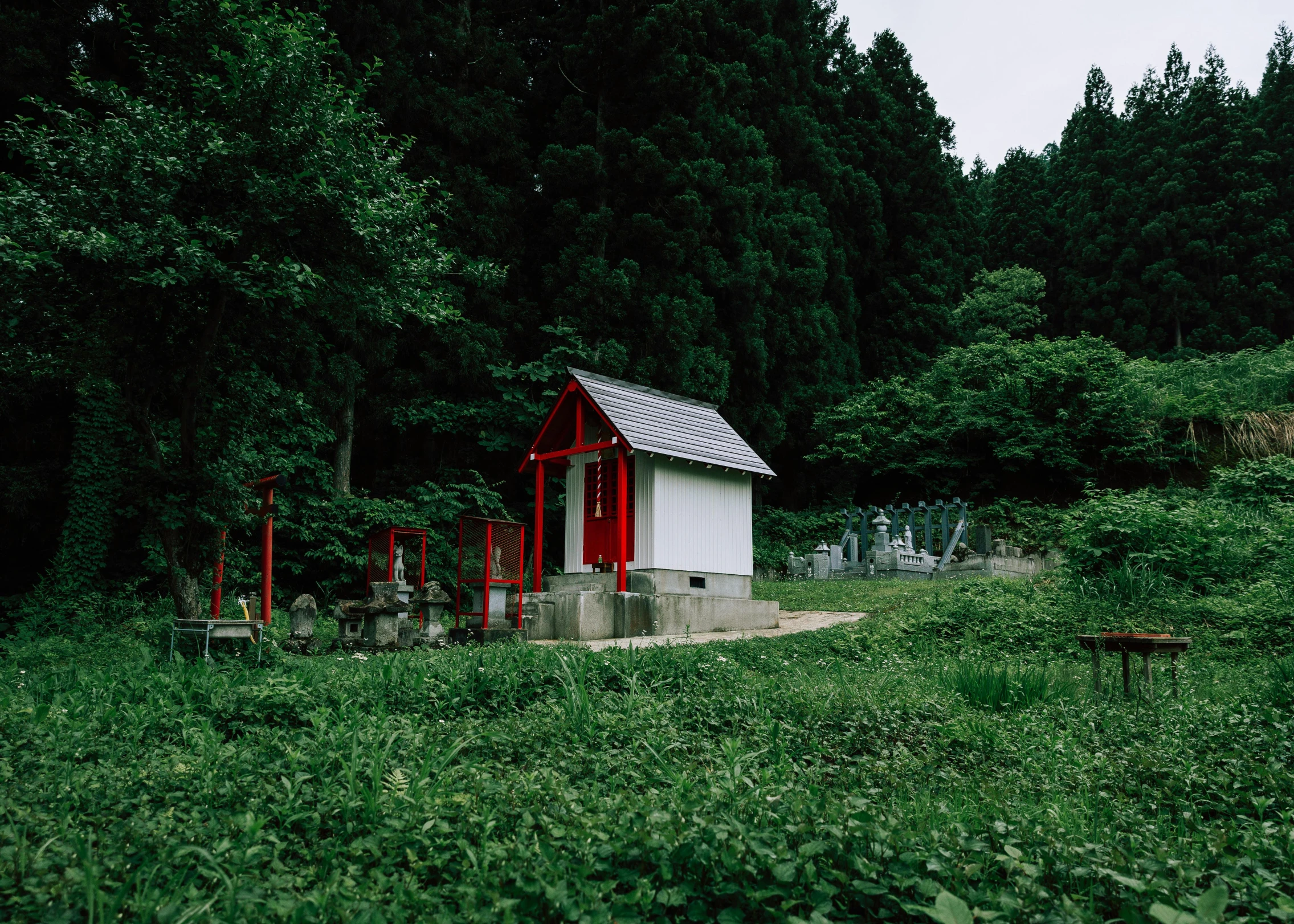 a small red and white cabin is standing on the edge of the field