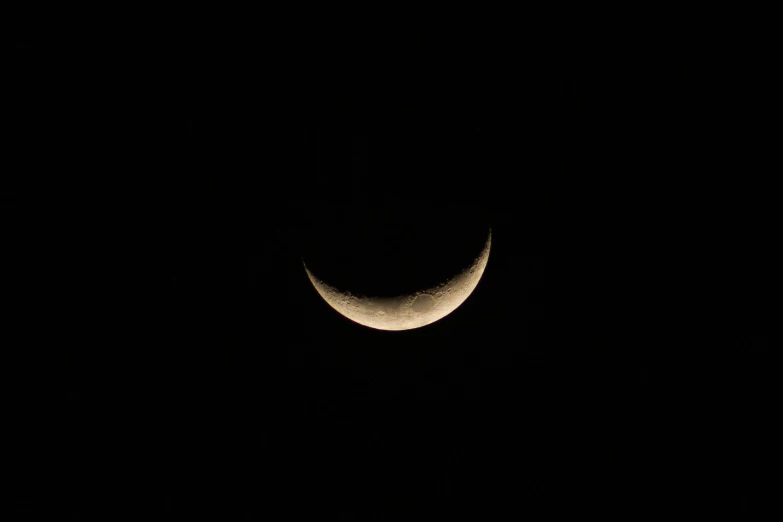 a half moon is seen in the dark sky