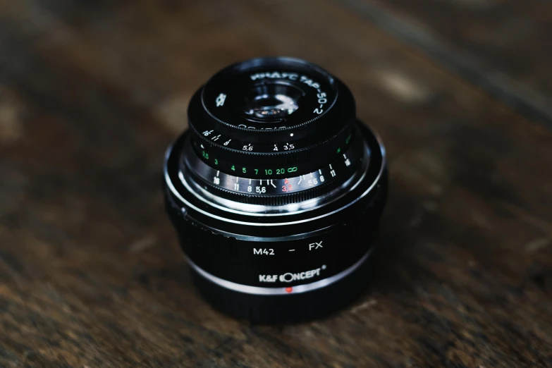 an analog camera on a wooden table with a lens in focus