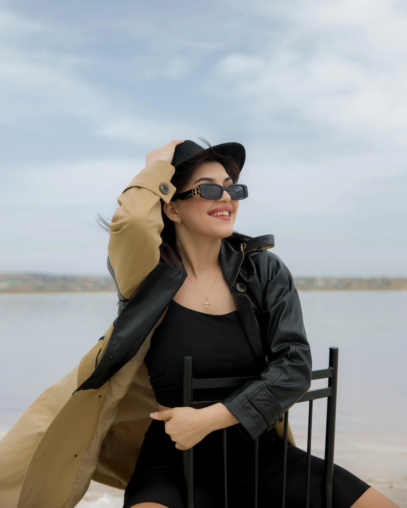 a woman posing next to the water in sunglasses