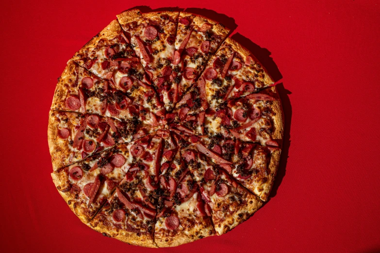 a pizza with pepperoni and cheese sliced into slices on a red background