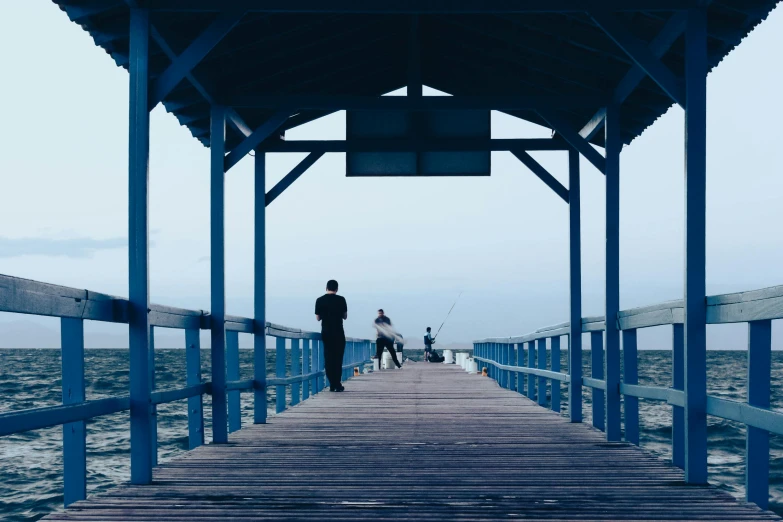 some people that are walking on a wooden pier