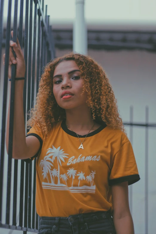 a beautiful young lady standing near a metal fence