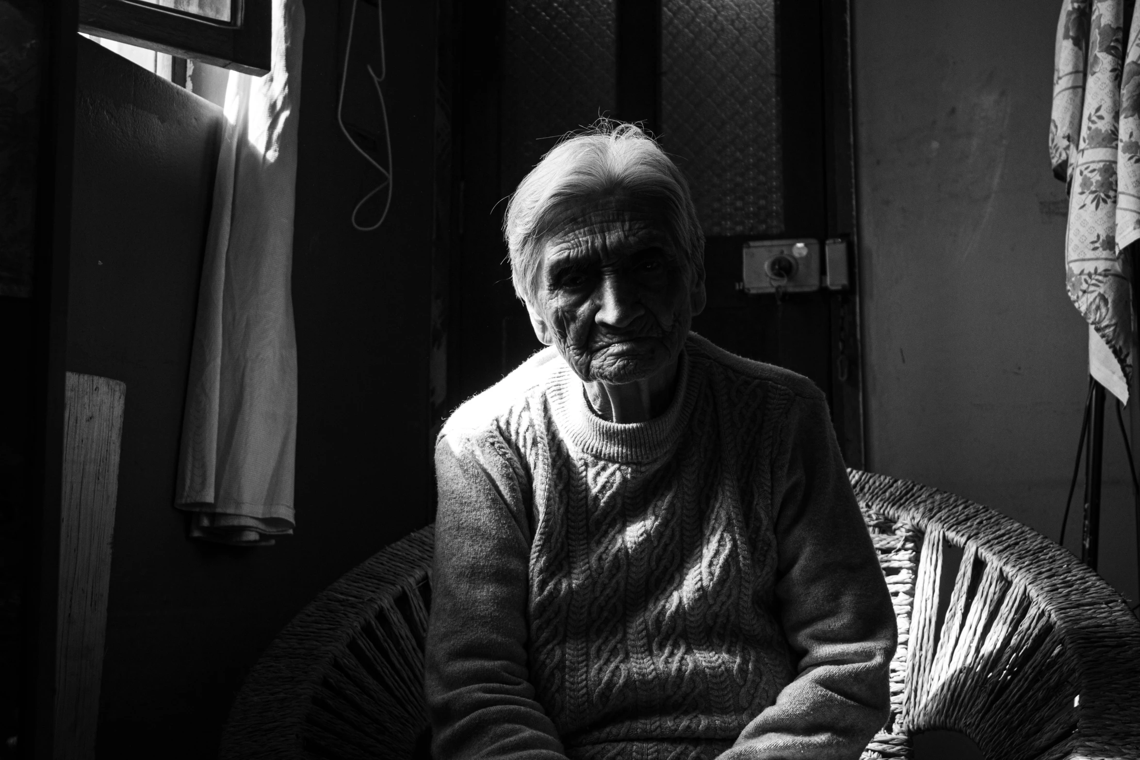 an elderly person sits inside a room by himself