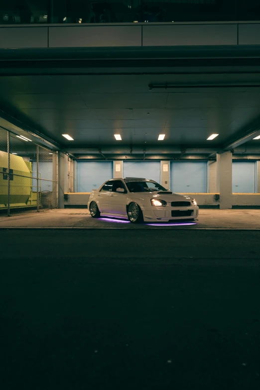 the white car is parked at the entrance to the parking garage