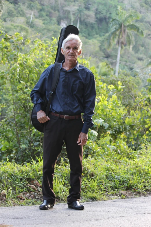 a man is standing on the side of the road wearing a backpack